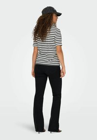 Gestreept katoenen t-shirt in zwart en wit met korte mouwen, gecombineerd met zwarte flare jeans en zwarte hak sandalen.