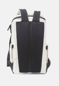 Rugzak met een crèmekleurige body en zwarte mesh-accenten. Voorzien van gevoerde schouderbanden, ritssluiting en zijzakken voor opslag.