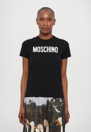 Černé bavlněné tričko s výrazným bílým nápisem "MOSCHINO" přes hrudník, doplněné tištěnou sukní s motivem hus.