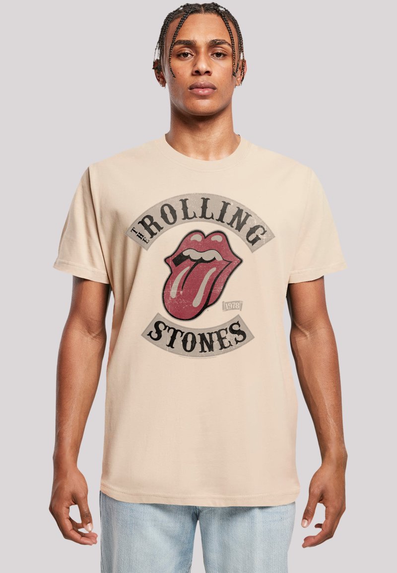 Beige katoenen t-shirt met een grote versleten graphic van het logo van de Rolling Stones, met een rode tong en zwarte tekst. Standaard pasvorm.