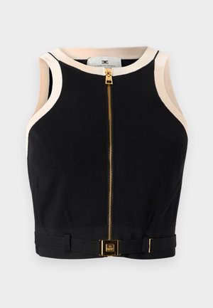 Haut court noir à texture côtelée, fermeture éclair dorée à l'avant, avec des accents crème le long du col et des emmanchures. Présente un détail de boucle dorée.