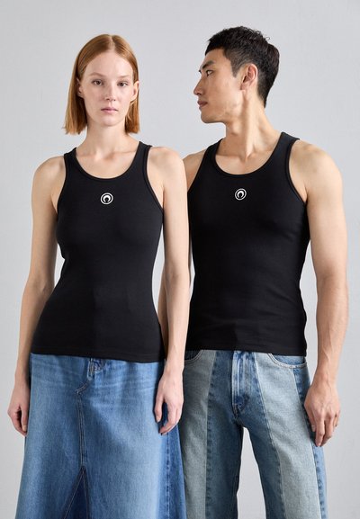 Zwei Modelle tragen eng anliegende schwarze Ripp-Top-Shirts mit einem kleinen weißen Logo in der Mitte. Der Hintergrund ist neutral und hebt die Kleidungsstücke hervor.