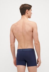 Mörkblå kalsonger av boxer-modell med en slät yta och ett kontrasterande blått resårband i midjan. Designen är tight och har en minimalistisk stil.