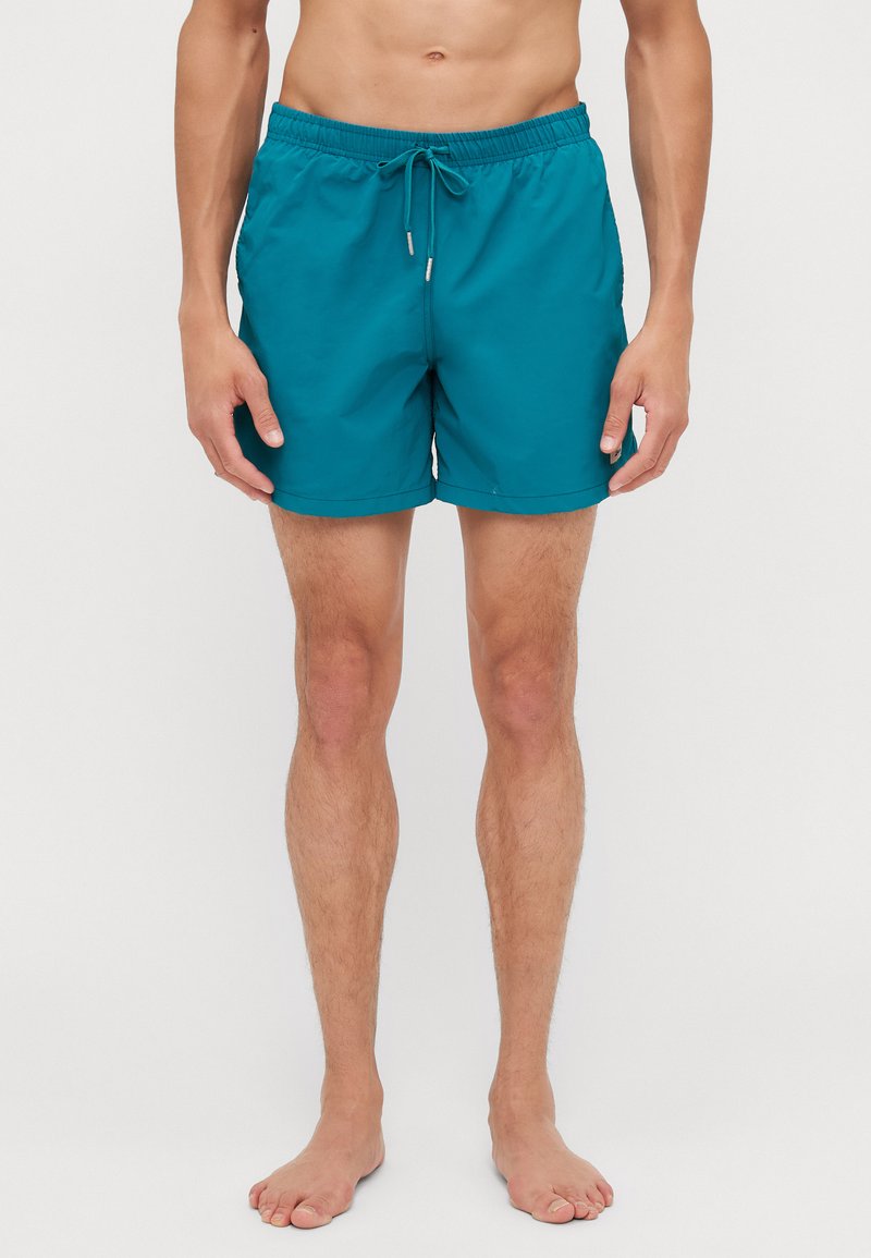 Shorts de bain turquoise avec une taille élastique et un cordon de serrage réglable. Fabriqués en tissu léger avec une texture lisse et sans motifs visibles.