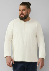 Langarm crème-kleurige henley-shirt met drie houten knopen bij de hals, met een licht gestructureerde stof en een relaxte pasvorm.