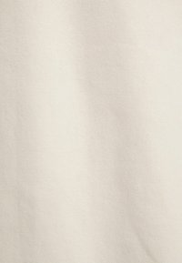 Tessuto di cotone di colore bianco sporco, con una texture liscia e una superficie uniforme, con modelli o imperfezioni minime visibili.
