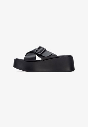 Sandalias de plataforma negras con una amplia correa ajustable con hebilla rectangular y una suela de textura lisa. Diseño simple y moderno.
