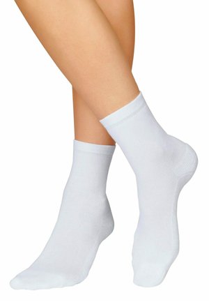 Weiße Baumwollknöchelsocken mit gerippten Bündchen, glatter Textur und ohne Muster, auf übereinandergelegten Beinen präsentiert.
