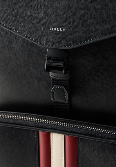 Black textured leather bag flap with black buckle, visible zipper, and vertical red and white leather stripes; "BALLY" logo in silver letters.