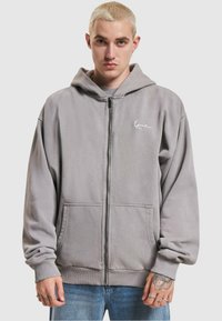 Gray zip-up hoodie in soft fabric, featuring a front kangaroo pocket, ribbed cuffs, and a small logo on the left chest.