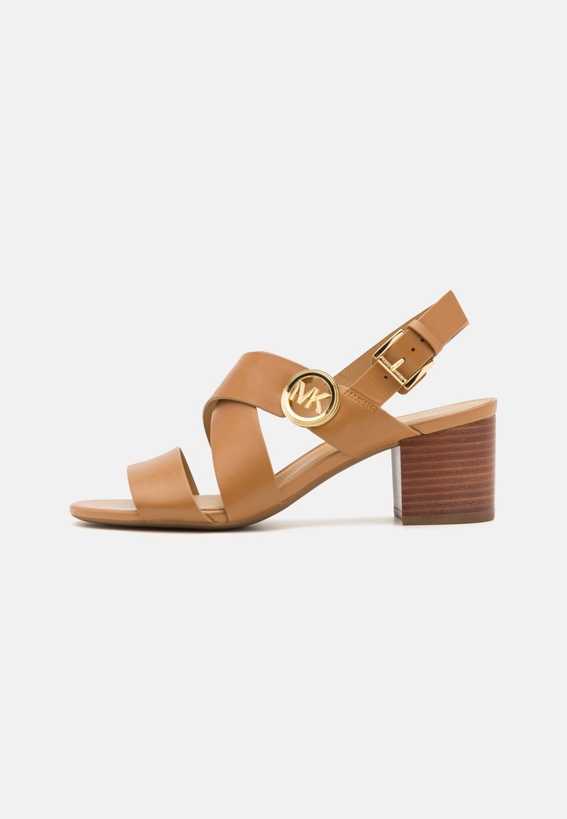 Sandale en cuir marron clair avec des brides croisées, logo circulaire doré, bride réglable avec boucle et talon bloc empilé.