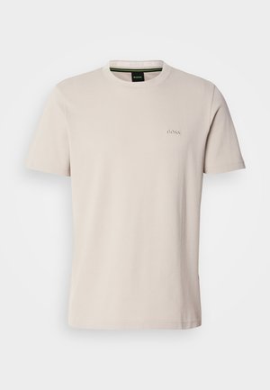 T-shirt de algodão bege claro com gola redonda. Apresenta um discreto logotipo bordado no peito. Mangas curtas e um design simples.