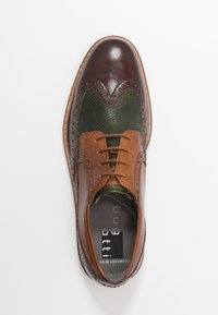Chaussure en cuir marron et vert avec des détails perforés, bout rond, lacets marron et un panneau d'accent couleur fauve. Semelle plate avec surface texturée.