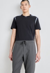 Sort t-shirt med blå skulderdetaljer og rund hals. Grå bukser med elastisk talje og justerbar snøre.