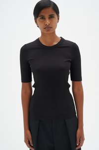 Melnas ribota īsām piedurknēm augšdaļa ar apaļu dekoltē un pieguļošu siluetu. Audumam ir teksturēta izskats, kas akcentē dizaina vienkāršību.