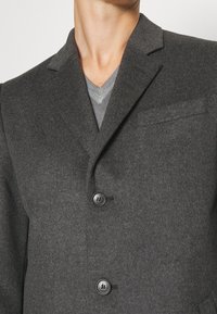 Blazer de lana gris con solapa de muesca, cierre de dos botones y un bolsillo en el pecho. Tejido texturizado con un acabado suave.