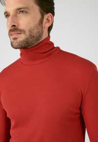 Red turtleneck sweater made of ribbed knit fabric, featuring a high collar, slim fit, and smooth texture. No patterns or hardware visible.