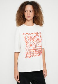 Λευκό βαμβακερό t-shirt με μεγάλο πορτοκαλί γραφικό που απεικονίζει ήλιο, φοινικόδεντρα και διακοσμητικά περιθώρια. Κοντά μανίκια και άνετη γραμμή.