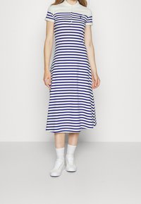 Pasiasta sukienka polo w białym i niebieskim kolorze, do kolan, z krótkimi rękawami, z zapięciem na guziki i małym logo na piersi.