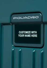 Harde koffer in turkoois met geribbelde textuur. Voorzien van een aanpasbaar naamlabel met witte tekst op een donkere achtergrond, merklogo van Piquadro.