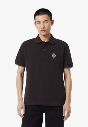 Polo nera in tessuto misto cotone, con colletto abbottonato e logo bianco a forma di diamante sul petto a sinistra. Maniche corte.