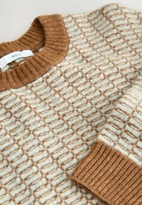 Knit sweater with a cream base and brown textured pattern. Features a ribbed brown crew neck and cuffs. Soft, thick fabric.