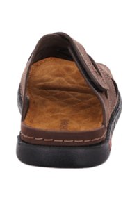 Sandale en cuir brun avec un dos ouvert, semelle intérieure texturée et semelle synthétique noire. Sangle Velcro pour un ajustement sécurisé.