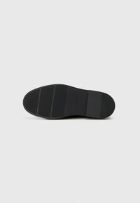 Semelle de chaussure noire en matériau en caoutchouc, surface texturée, trois rainures horizontales et zones lisses. Design minimaliste sans fonctionnalités supplémentaires.