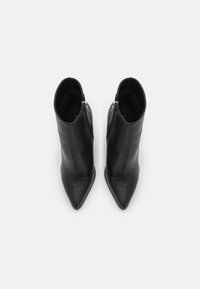Bottines en cuir noir à bout pointu avec une finition lisse et élégante. Dotées d'une fermeture éclair sur le côté et de coutures discrètes.