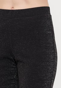 Mustad, elastsed leggings läikiva tekstuuriga ja siledast vöökoht. Kangas sisaldab peent säraefekti lisadetailiks.