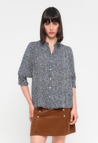 Navy leopard print blouse with a button-down front and three-quarter sleeves, paired with a brown corduroy skirt featuring silver buttons.