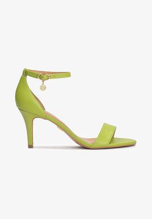 Sandalia de tacón alto de cuero verde con correa en el tobillo, puntera abierta y pequeño charm dorado en la hebilla, mostrada en perfil lateral.