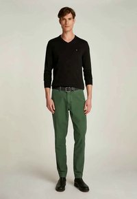 Sweater preto em V, calças verdes, cinto preto, sapatos pretos elegantes. Design simples, bem ajustado, textura de tecido suave. Sem padrões ou detalhes.