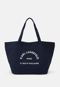 Granatowa torba płócienna z dwoma uchwytami. Zawiera biały napis: "KARL LAGERFELD PARIS 21 RUE ST-GUILLAUME" w zakrzywionym wzorze. Przestronna konstrukcja.