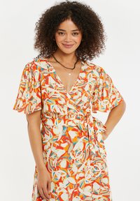 El vestido envolvente presenta un colorido patrón abstracto con tonos de naranja, blanco y azul. Tiene mangas cortas abullonadas y un diseño de cintura con lazo.
