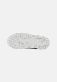 Suola di sneakers bianche con motivi testurizzati, accenti circolari e scanalature per una migliore aderenza; presenta un design piatto per stabilità e supporto.