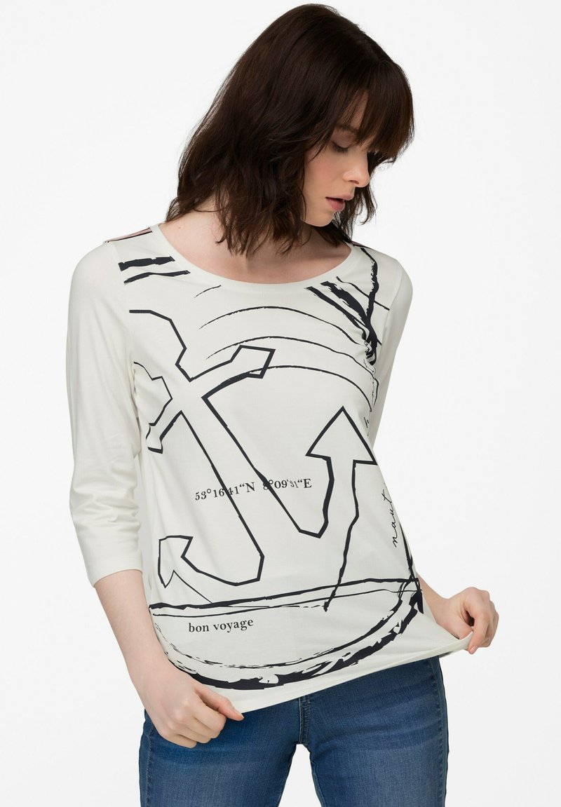 Weißes Langarm-T-Shirt mit schwarzem Anker- und Kompassdesign, Rundhalsausschnitt und lockerer Passform. Bedruckter Text lautet "bon voyage".