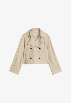 Veste beige courte à double boutonnage avec larges revers, quatre boutons foncés, manches longues et deux poches latérales verticales.