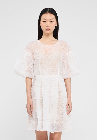 Robe blanche avec un motif floral texturé, en matière transparente, et des manches bouffantes. Le design présente un col rond et une silhouette évasée.