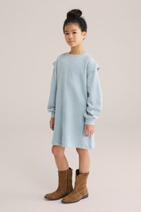Svetlo modra pulover obleka iz mehke tkanine, z dolgimi rokavi, nabrano ramenskimi detajli in poudarki. V kombinaciji s svetlo rjavimi semiš čevlji.