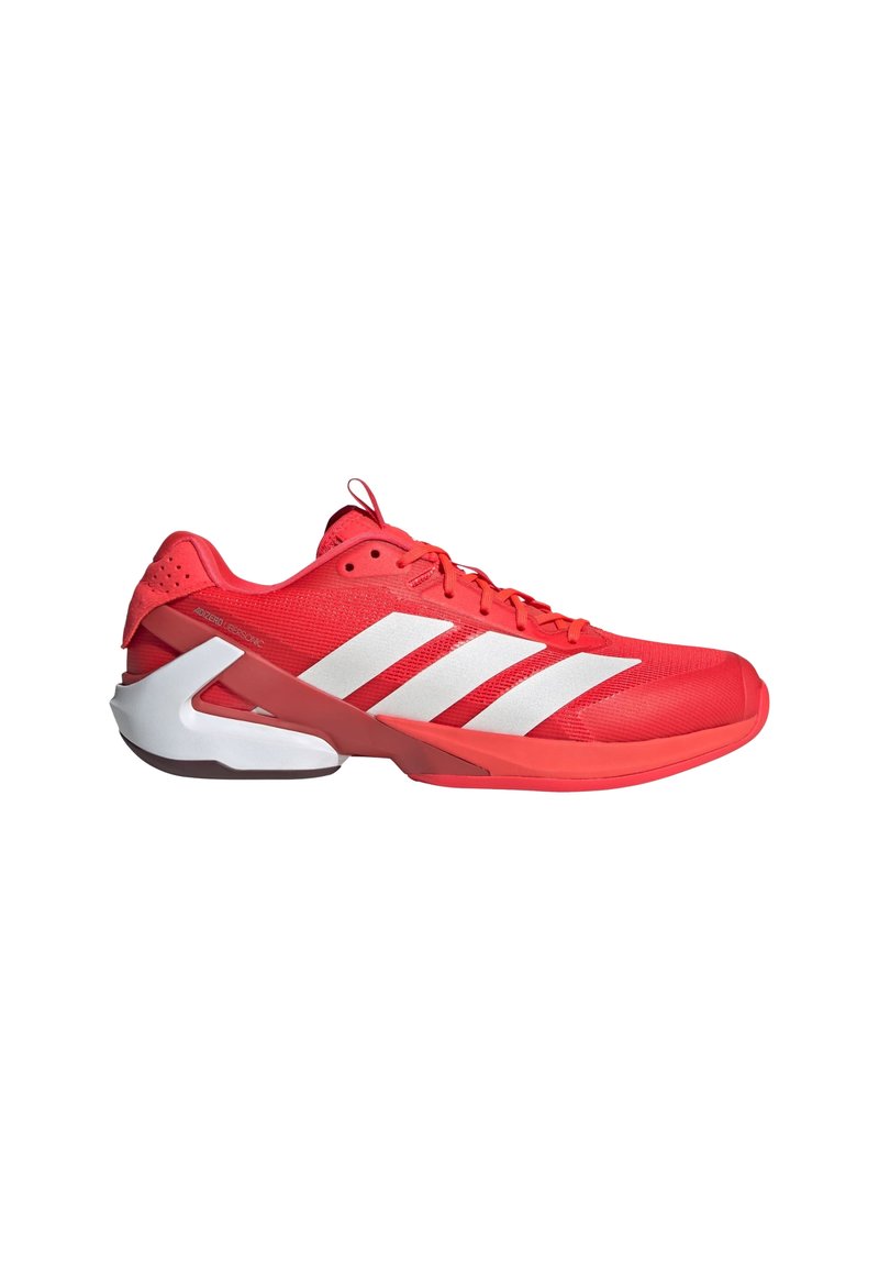 Chaussure de sport rouge avec des rayures blanches, tige en maille, collier rembourré et design de semelle incurvée distinctif. Comprend des lacets et un bout renforcé.
