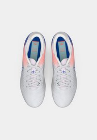 Ζευγάρι λευκών αθλητικών παπουτσιών με ροζ λεπτομέρειες και μπλε σόλες, προσανατολισμένο από πάνω σε λευκό φόντο.