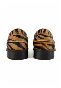 Animal-print shoes featuring a brown and black tiger stripe pattern, made from textured fur, with a solid black rubber sole.