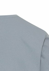 Lyseblå T-shirt med en blød, glat overflade. Har en rund halsudskæring og korte ærmer. Sømdetalje synlig nær skulderen.