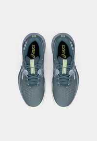 Sportssko i en teal og grå farveskema. Funktioner inkluderer åndbart mesh-overdel, perforerede detaljer og lime-accenter.