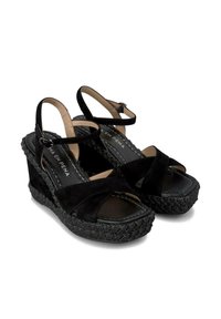 Schwarze Wildleder-Wedgesandalen mit überkreuzten Riemen, gepolstertem Fußbett und strukturiertem geflochtenem Plateau. Verstellbarer Knöchelriemen enthalten.