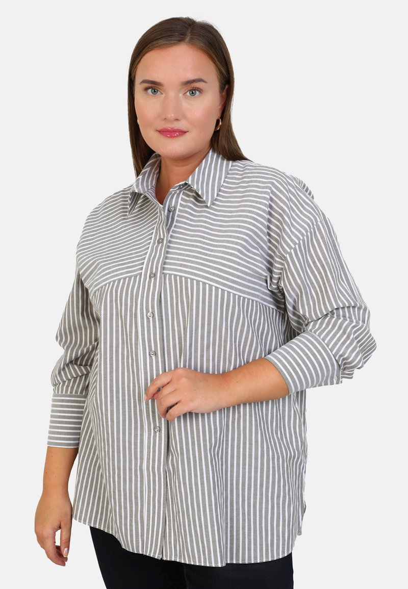 Chemise à rayures grises et blanches avec un col pointu, des manches longues et un détail de poche avant. Texture en tissu doux et tissé.