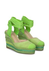 Sandales vertes à talon avec un tissu texturé, des accents tissés et une semelle espadrille à motifs. Présente un bout rond et des lanières à lacets autour de la cheville.