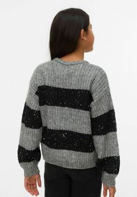 Szary i czarny sweter w paski o teksturowanym splocie, z czarnymi paskami ozdobionymi cekinami oraz ściągaczem przy kołnierzu i mankietach.