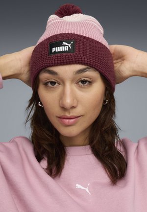 Knit beanie in maroon with light pink and white stripes, topped with a pom-pom. Features a black PUMA logo patch on a textured band.
